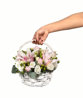 White basket of pink lilies, pink tulips, and white eustoma flowers.